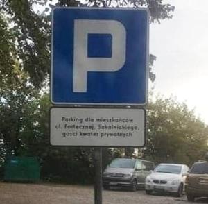 桑多梅日Zielone Wzgórze na Starówce的蓝色的停车标志,汽车停在停车场