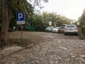 桑多梅日Zielone Wzgórze na Starówce的停车场有停放的汽车和蓝色的停车标志