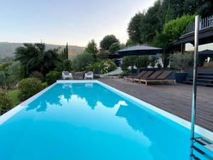 比索达雷加Casa da Horta的蓝色游泳池配有椅子和遮阳伞