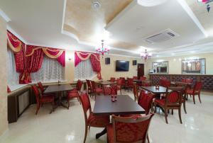 喀山维罗纳名誉酒店的餐厅设有木桌和红色椅子