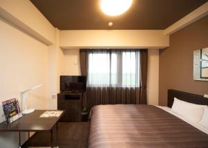 IshiokaHotel Route-Inn Ishioka的酒店客房,配有床和电视