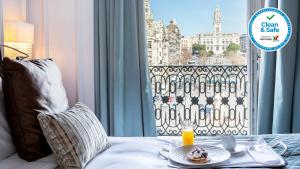 波尔图洲际波尔图酒店 - 卡多佐宫的一张桌子,上面有盘子的食物放在床上,有窗