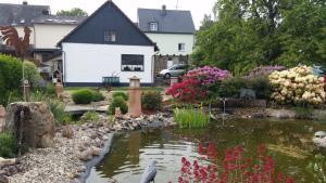 OsburgFerienwohnung Vergissmeinnicht的房屋前带池塘的花园