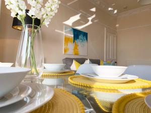 邓迪Tay View Apartment的白色餐具玻璃桌和花瓶