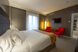 杜兰戈Silken Gran hotel Durango的酒店客房,配有一张床和两张红色椅子