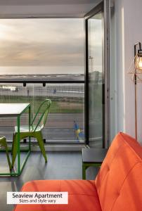 布莱克浦ApartHotel421 by Seafront Collection的客厅配有橙色沙发、桌子和窗户