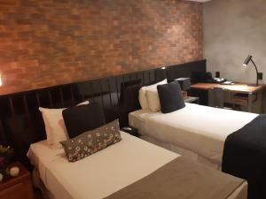 圣保罗Hotel Heritage的酒店客房带两张床和砖墙