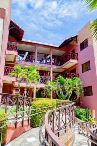 纳塔尔Pousada Vale do Sul的一座粉红色的建筑,设有阳台和树木