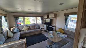塔特舍尔Luxury 2019 8 berth Caravan with Hot Tub @ Tattershall Lakes的客厅配有沙发和桌子