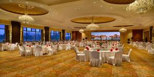 鄂尔多斯鄂尔多斯皇冠假日酒店的宴会厅配有白色的桌椅和吊灯