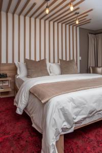 布隆方丹LOCH LOGAN HOTEL的一张白色的大床,位于带条纹墙的房间里