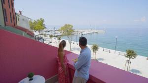 奈维斯Veya Hotel by Aminess的站在一个水景阳台上的男人和女人