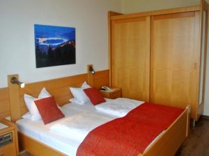 阿尔特芬肯施泰恩鲍加特纳赫夫酒店的一间卧室配有带白色床单和红色枕头的床。