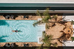 蒂加基More Meni Residence & Suites的在配有太阳镜的游泳池游泳的人