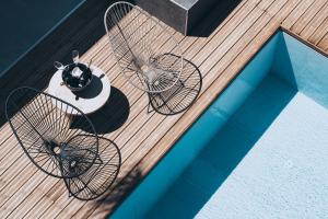 蒂加基More Meni Residence & Suites的游泳池畔的甲板上配有两把椅子和一张桌子