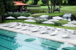巴耶德布拉沃阿瓦达罗高尔夫及Spa度假酒店的高尔夫球场旁带椅子和遮阳伞的游泳池