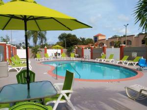 迈尔斯堡Quality Suites Fort Myers Airport I-75的游泳池配有椅子和桌子及遮阳伞