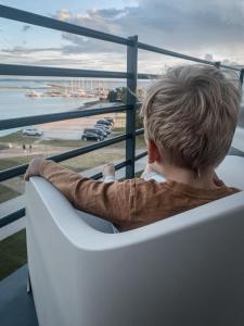 库雷萨雷Ö Seaside Suites & SPA的坐在椅子上看着大海的男孩