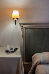 古比奥杜卡勒酒店的卧室,桌子旁的电话在台灯旁