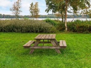 安斯艾厄10 person holiday home in Ansager的湖畔草地上的木餐桌