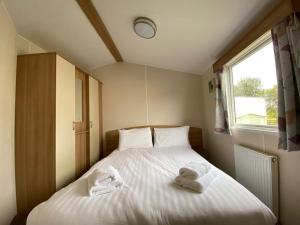 米勒姆Holiday in Caravan的卧室配有带2条毛巾的窗户,位于床上