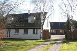 HarlevStenbrogård的白色的房子,有黑色的屋顶和车道