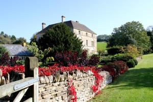 NauntonAylworth Manor的房屋前方有红色花的石墙