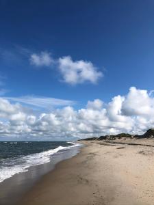 乌尔夫堡Fjand Badeby - Guesthouse, Cottages and Colony的一片沙滩,上面有海洋和天空的云