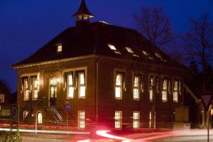 Heeswijk-DintherRaadhuis Dinther Suites的一座大型建筑,晚上有窗户照明