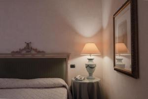 古比奥杜卡勒酒店的一间卧室配有一张床、一盏灯和一面镜子