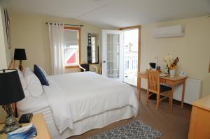 卢嫩堡海盗湾旅馆的卧室配有白色的床、书桌和桌椅