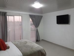KwamhlangaLesiba guesthouse的卧室配有一张床,墙上配有电视