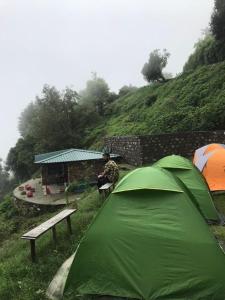 穆索里SERENITY CAMPS, MUSSOURIE的坐在帐篷旁长凳上的人