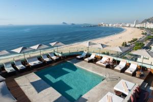 里约热内卢里约热内卢波尔图湾酒店的海滩旁的游泳池,配有遮阳伞