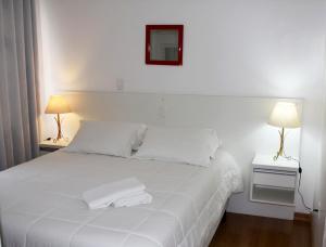 格拉玛多SANTA CLAUS 2 - Centro de Gramado的卧室配有白色的床和2条毛巾