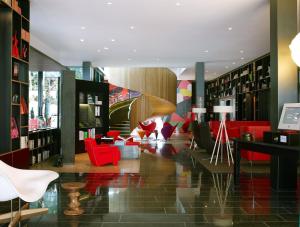 伦敦伦敦泰晤士河畔世民酒店的图书馆配有红色椅子和书架