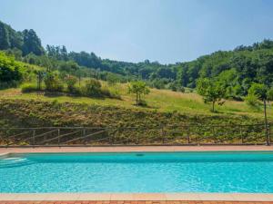 塞拉瓦莱皮斯托耶塞Apartment Crepuscolo by Interhome的一座树木繁茂的山丘前的游泳池
