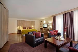 上施陶芬Hotel Bavaria - Partnerbetrieb von Oberstaufen PLUS的带沙发和椅子的客厅以及卧室