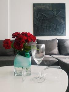 诺维萨德Apartment IRIS的一张桌子,上面有红玫瑰花瓶和葡萄酒杯
