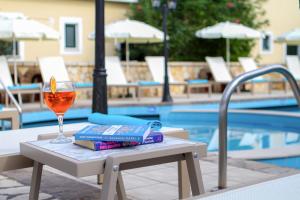 阿查拉维Navigator Villas - Houses的一杯葡萄酒和一本书放在游泳池畔的桌子上