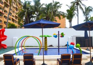 马萨特兰马萨特兰酒店的游泳池旁的游泳池配有椅子和遮阳伞