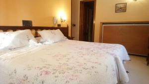 塞哥维亚Hostal Don Jaime I y II的卧室配有白色的床铺,上面有粉红色的鲜花