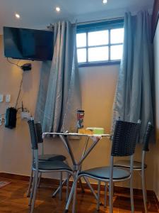 阿拉亚尔-杜卡布Suites Oliveira的窗户间里的一张桌子和两把椅子