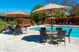 弗雷斯诺皮卡迪利酒店的游泳池畔的桌椅和遮阳伞