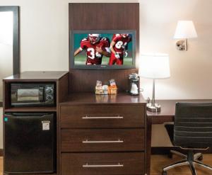 马纳萨斯红屋顶PLUS客栈 +华盛顿特区 - 马纳萨斯的客房设有书桌和带足球播放机的电视。