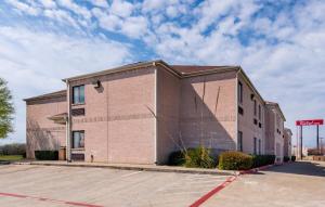 沃思堡Red Roof Inn Fort Worth - Saginaw的砖楼前的一个空停车位