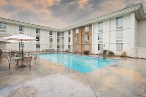 诺克斯维尔Red Roof Inn Knoxville Central – Papermill Road的大楼前的带椅子和遮阳伞的游泳池