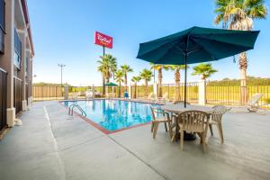 哈蒙德Red Roof Inn PLUS+ Hammond的游泳池旁配有桌椅和遮阳伞