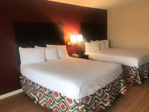 圣安吉洛Red Roof Inn & Suites San Angelo的配有白色床单的酒店客房内的两张床
