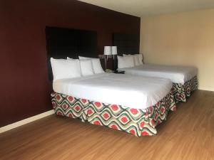 圣安吉洛Red Roof Inn & Suites San Angelo的两间相邻的床铺位于酒店客房内